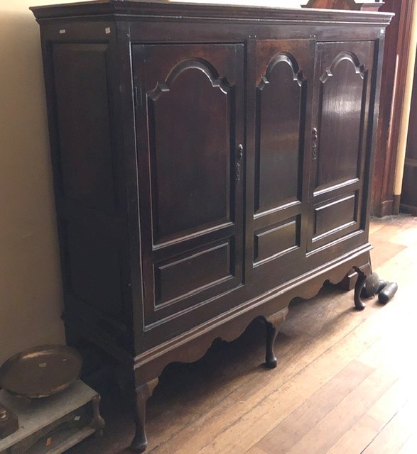 An early 18th Century oak linen press on stand, circa 1710, moulded cornice, above three panel