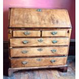 A George II walnut and cross banded bureau, circa 1740, the fall enclosing a fitted interior with