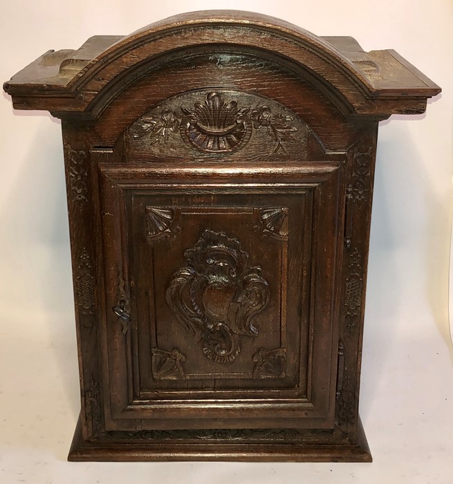 A 17th Century French oak sacristy cabinet, an arch moulded top above a carved single panel door