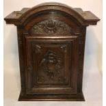 A 17th Century French oak sacristy cabinet, an arch moulded top above a carved single panel door