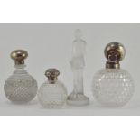 Three early 20th Century silver topped cut glass scent bottles, together with a frosted glass figure