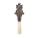 A George V novelty silver baby's rattle handle in the form of an owl, blue glass eyes, mother of