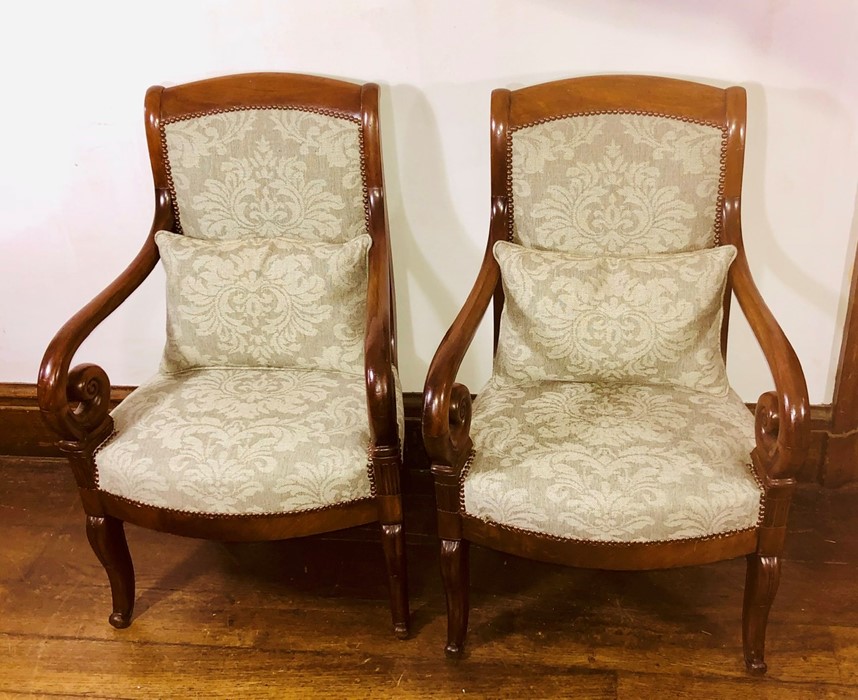 A pair of French design mahogany armchairs, upholstered back and seat with brass studs, scrolling