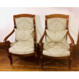 A pair of French design mahogany armchairs, upholstered back and seat with brass studs, scrolling