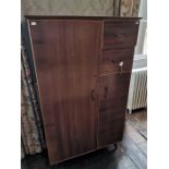 A mid 20th Century teak compactum tallboy, fitted with a single door to left, with two drawers and a