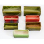 A group of Bretby art pottery green glazed and red glazed planters: Largest 29 cm long. (7)