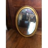 A gilt framed oval wall mirror.