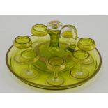 A early 20th Century green glass liquer set, comprising a liquer decanter, seven glasses and