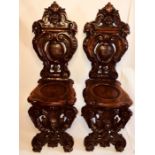 A pair of 19th century Italian Renaissance walnut Sgabello hall chairs, carved coat of arms and