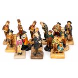 A collection of Bretby art pottery bluff decorated Dickensian figures including the Artful Dodger,
