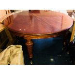 A Victorian Revival mahogany dining room table with extra leaves.