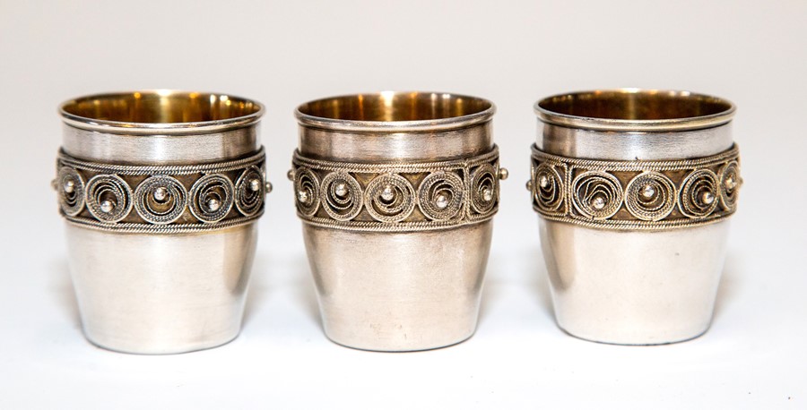 A set of three Russian silver vodka tots, gilt interiors with filigree and bead borders, each with