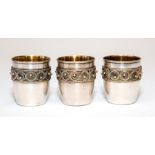 A set of three Russian silver vodka tots, gilt interiors with filigree and bead borders, each with