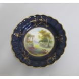 A Royal Worcester Plate with a deep Blue and gilt ground border and scalloped rim. The centre