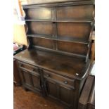 An Ercol elm dresser and rack, two tier shelving above two short drawers and two cupboards.