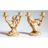 A pair of Royal Worcester blush ivory boy and girl candlesticks, both signed Hadley, each