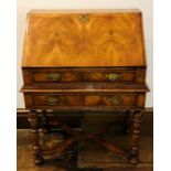 A Queen Anne revival walnut and featherbanded bureau on stand, fall front enclosing pigeon holes,