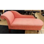 A traditional pink upholstered chaise longue, of recent manufacture, raised on turned legs, with