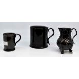 A mid 18th Century black glazed earthenware sparrow beak jug, of baluster form, with three feet, a