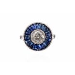 A diamond and sapphire platinum set ring, the central rub-over set round brilliant cut diamond