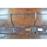 A collection of 5 antique coat hooks on a section of wood with 3 attached number plates