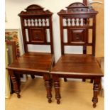 A pair of late Victorian mahogany hall chairs, floral and scroll carved arch top, above turned