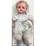 An early 20th Century German AM & M celluloid doll, clothed with a green dress and pyjamas, damage