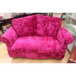 A contemporary two seater settee, the arms reclining, upholstered in a pink velvet covering, with
