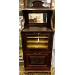 An Edwardian mahogany music cabinet, carved back rail and inset mirror, the glass door enclosing