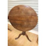 A George III oak tripod table, circa 1770, the circular three plank top raised on a turned column