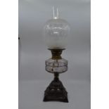 A late Victorian oil lamp with metal base, glass globe and clear paraffin body