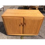 An Ercol Windsor range ash two door cabinet, one handle rotating and securing the door, 68cm high,