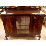 A mid 20th Century mahogany sideboard, serpentine form, having a serpentine back rail to top, glazed