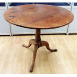 An early 19th Century oak tilt top tripod table, the three plank top raised on a turned column,