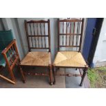 A pair of Arts and Crafts oak spindle back chairs, with rush seats, together with a pair of