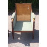 An early 19th Century mahogany bergere chair, circa 1830, with a canework back, padded arms and