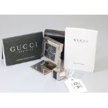 Gucci. A stainless steel travelling clock, the black enamel dial with baton markers and internal min