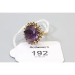 An amethyst dress ring, the large circular cut amethyst within a border of clear stones, basket mou