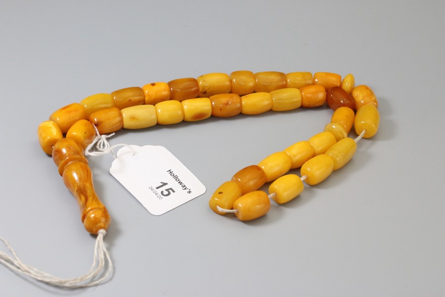 An amber bead necklace of barrel shaped mixed coloured links, to a knopped pendant, approximately 68