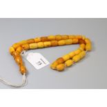 An amber bead necklace of barrel shaped mixed coloured links, to a knopped pendant, approximately 68