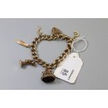 A 9ct gold curb pattern bracelet with padlock clasp, suspending five charms including a seal and a t