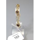 A garnet set 18ct gold bracelet, the five oval cut garnets in pierced scroll mounts between waisted