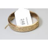 A 9ct gold bangle foliate engraved to centre with push button clasp, 10.68g