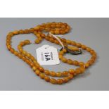 An amber bead necklace of small uniform sized oval beads with tassel set pendant, approximately 51cm