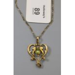 An Edwardian 9ct gold peridot negligée pendant, the central oval peridot in scroll-work frame with p