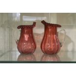 A pair of cranberry glass jugs,