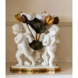 A Moore Brothers centrepiece, modelled as three putti supporting a giant lily, 22cm high.
