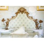 A French rococo style parcel gilt wood and gesso headboard, 19th Century, of shield form, carved