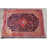 An early 20th Century hand knotted woollen rug, symmetrical decoration with stylised floral patterns
