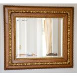 A late Victorian oak and parcel gilt wall mirror, circa 1890, the rectangular bevelled plate